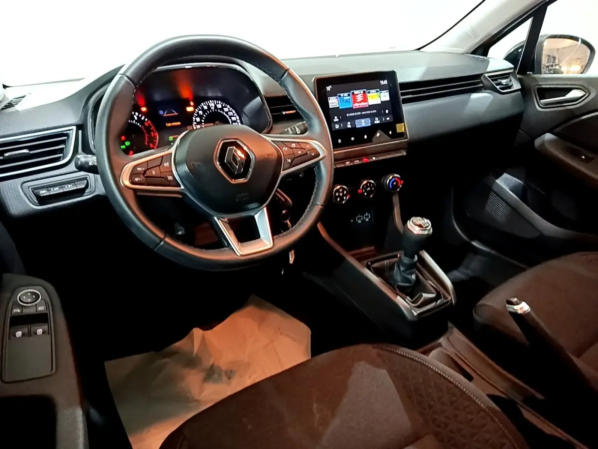 Vue intérieure côté conducteur de la Renault Clio gris clair 2023, volant cuir multifonctions et écran tactile central.