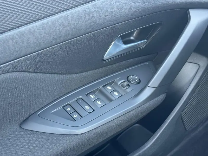 Vue rapprochée de la porte avant gauche de la Peugeot 308 2025, avec commandes électriques et poignée grise.