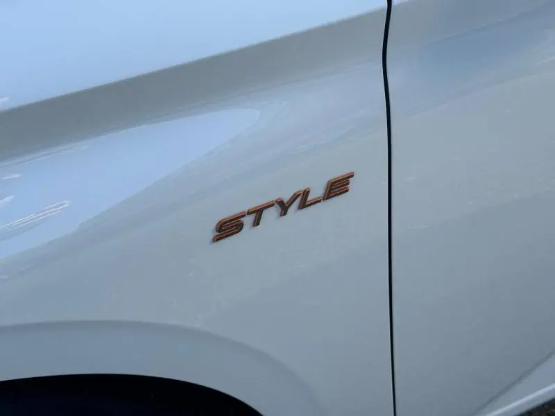 Gros plan sur l’inscription Style en relief couleur cuivre sur la portière avant droite d’une Peugeot 308 blanc Okénite.