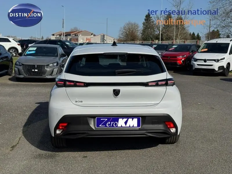 Vue arrière d'une Peugeot 308 blanche Okénite avec feux LED distinctifs et logo noir au centre du hayon.
