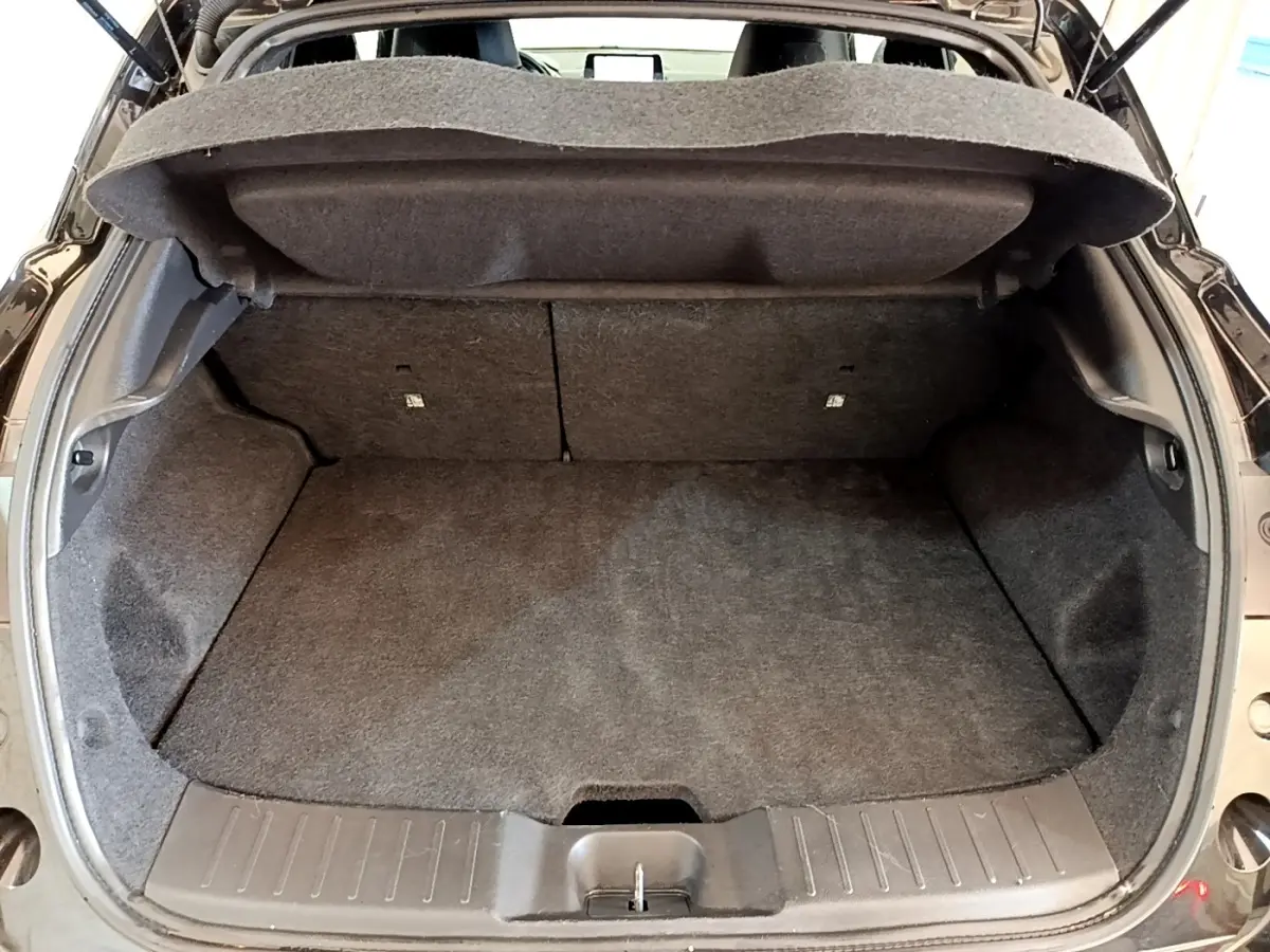 Coffre ouvert vu de l'arrière d'un Nissan Juke noir 2022, montrant l'espace de chargement vide et la tablette de coffre relevée.