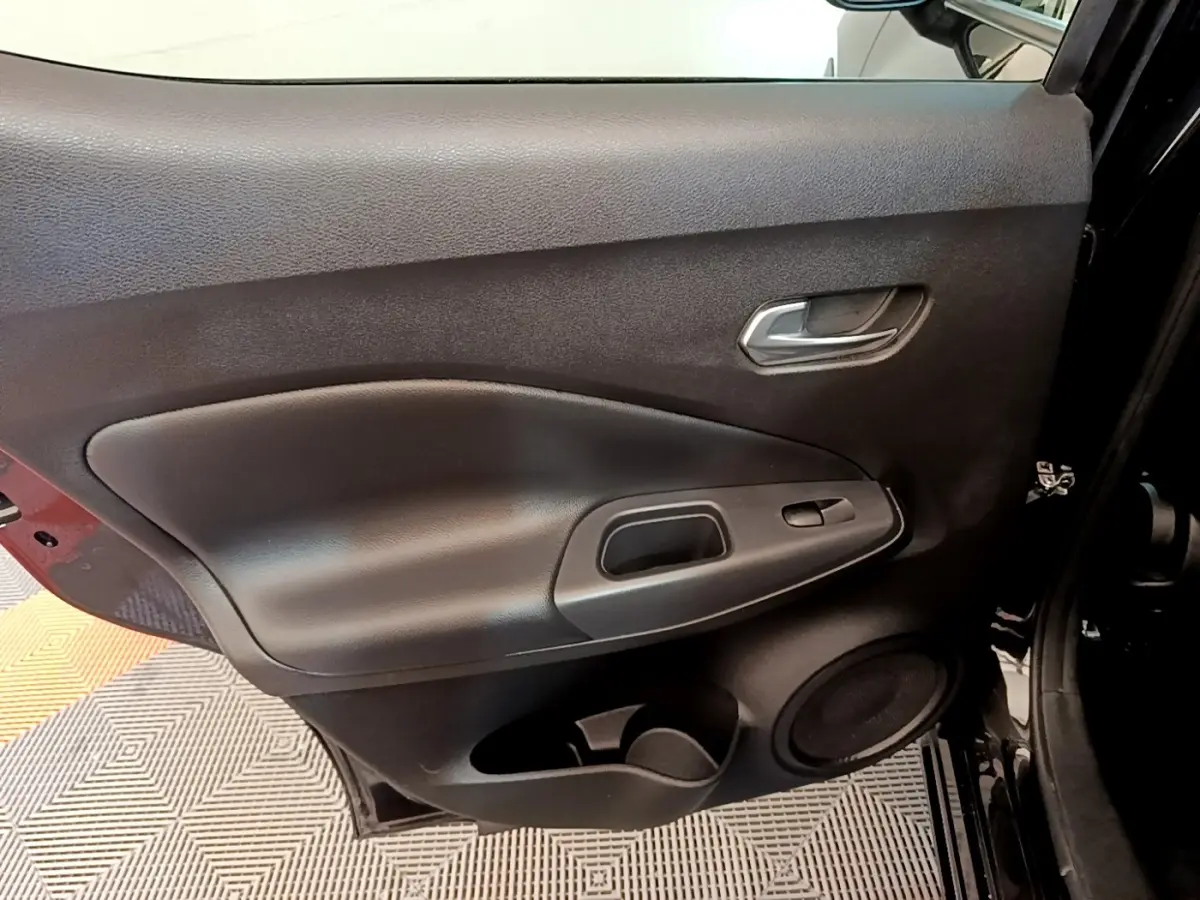 Vue intérieure de la porte arrière gauche noire du Nissan Juke 2022 avec poignée et haut-parleur intégrés.