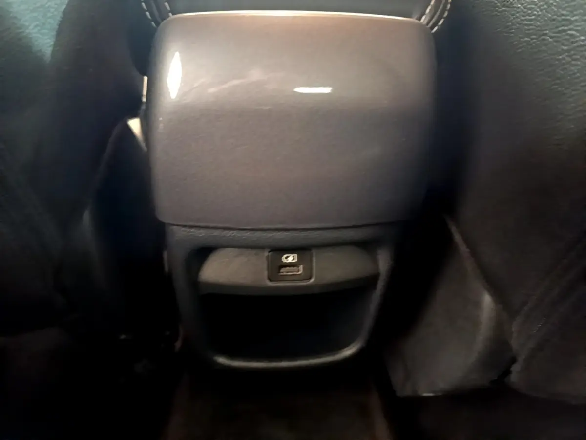 Vue rapprochée de la console arrière noire du Nissan Juke 2022 avec prise USB visible entre les sièges avant.