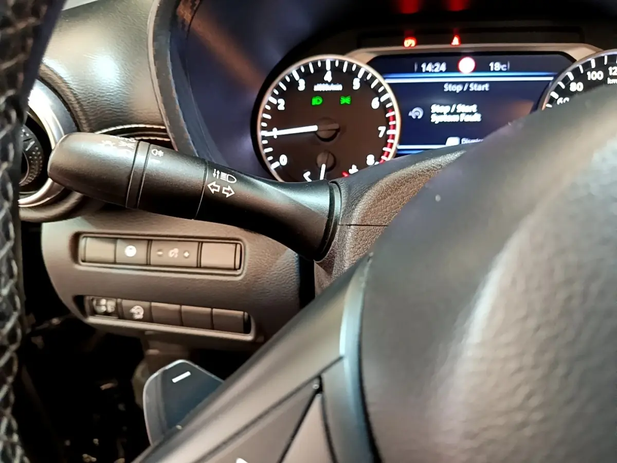 Gros plan sur le volant et le combiné d'instruments numérique du Nissan Juke noir, affichage multifonctions visible.