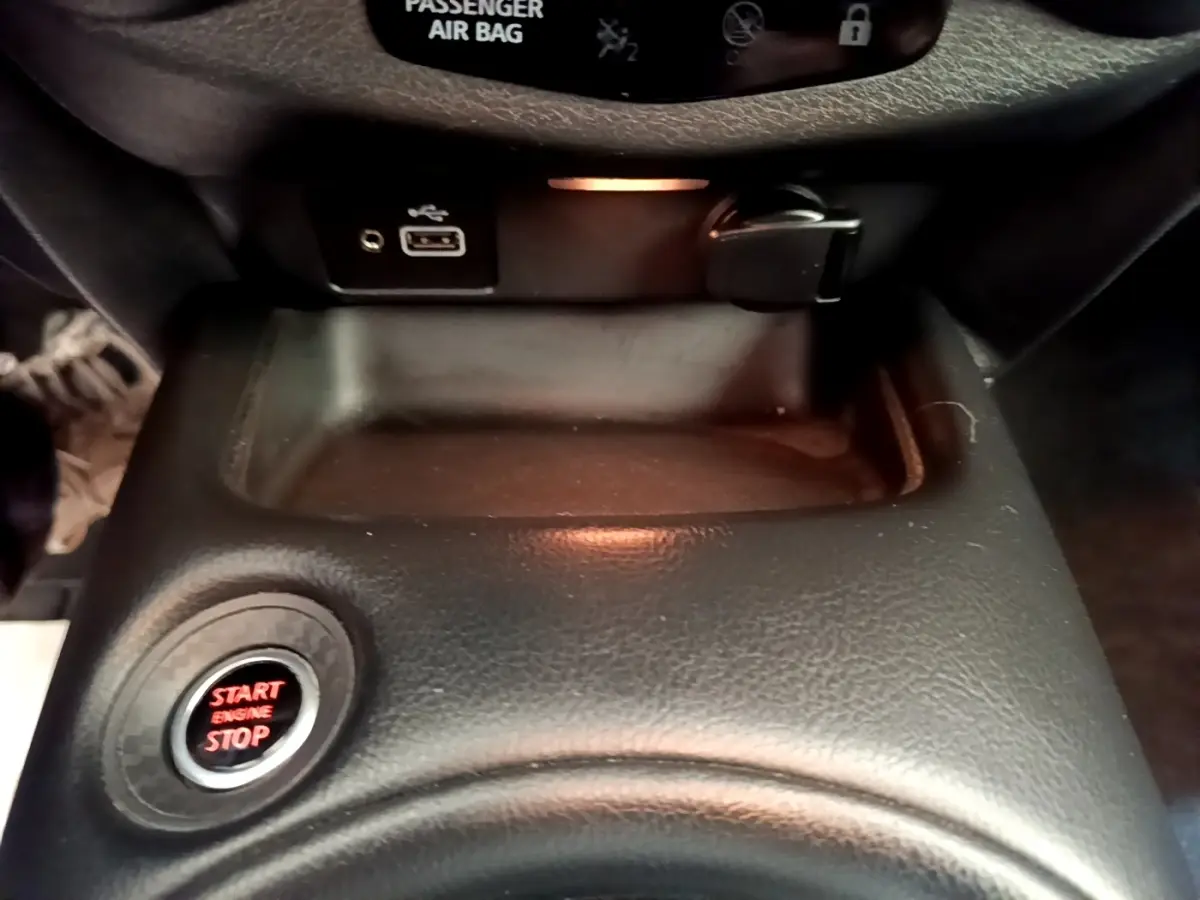 Gros plan intérieur sur la console centrale noire du Nissan Juke 2022 avec bouton start/stop rouge et prise USB visible.