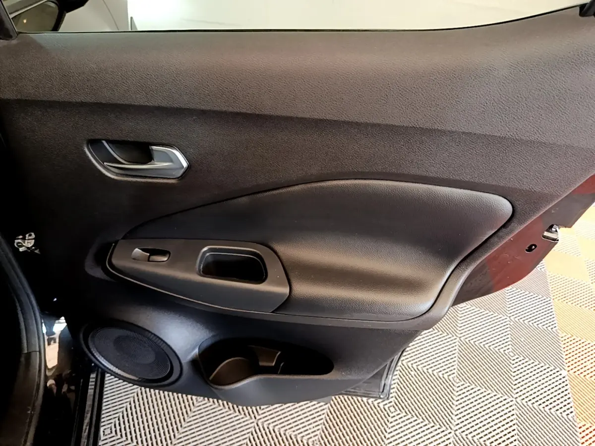 Vue intérieure côté gauche de la porte noire du Nissan Juke 2022 avec poignée, haut-parleur et rangement intégré.