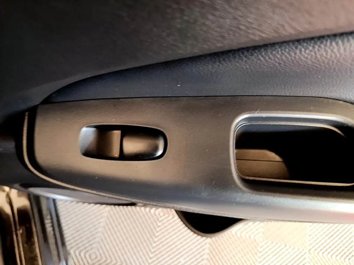 Détail de la poignée intérieure noire de porte côté conducteur du Nissan Juke DIG-T 114 DCT 2022.