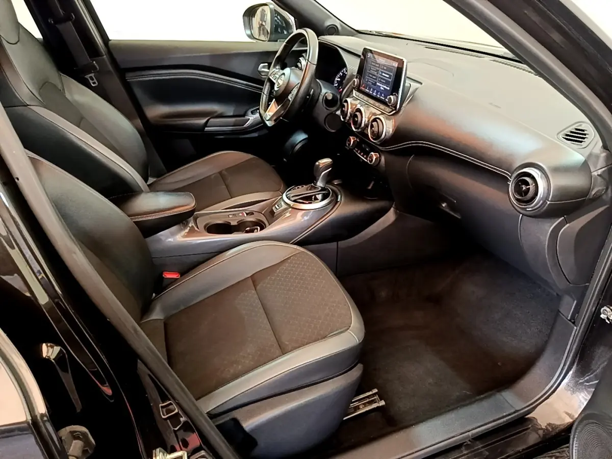 Vue intérieure côté conducteur du Nissan Juke noir 2022, avec tableau de bord moderne et écran tactile central.