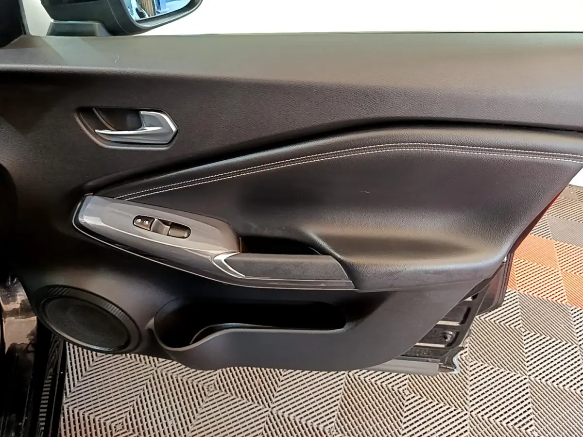 Vue intérieure du panneau de porte côté conducteur noir avec commandes des vitres et haut-parleur intégré sur Nissan Juke 2022.