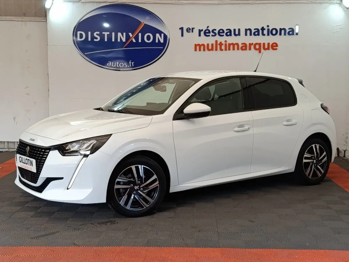 Peugeot 208 blanc vue de profil côté gauche, avec jantes alliage et feux avant LED visibles en intérieur showroom.