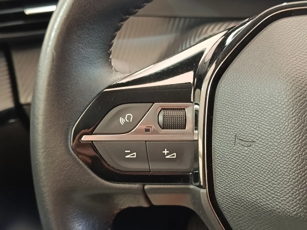 Gros plan sur les commandes gauche du volant cuir noir du Peugeot 208 PureTech 100 S&S Allure Business.