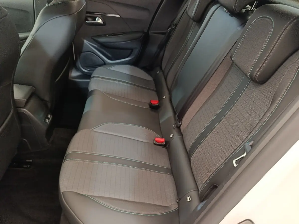 Vue intérieure côté droit montrant la banquette arrière en tissu gris et cuir noir de la Peugeot 208 blanche.