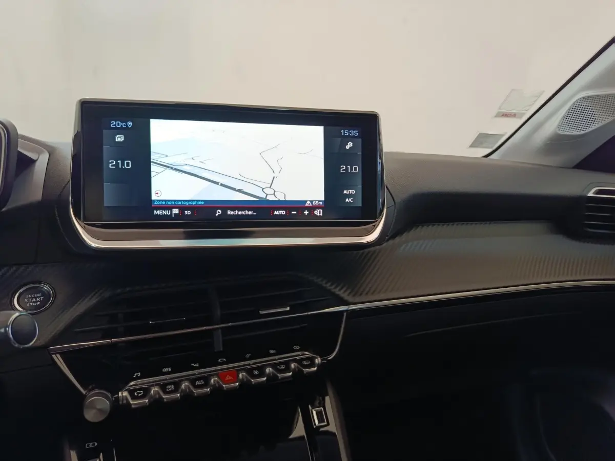Vue intérieure du tableau de bord de la Peugeot 208 blanche, avec écran tactile de navigation 10 pouces et commandes intégrées.