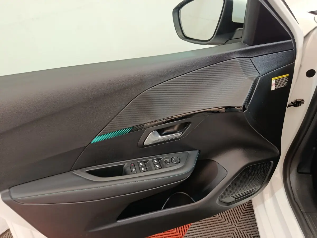 Vue rapprochée de la porte avant gauche blanche d'une Peugeot 208 2021 avec garniture noire et commandes électriques.