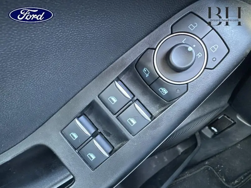 Gros plan sur les commandes des vitres électriques et rétroviseurs d'une Ford Puma blanc glacier, côté conducteur.