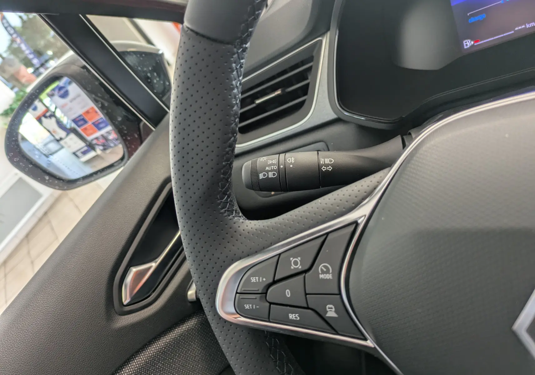 Gros plan sur le volant perforé et les commandes multifonctions du Renault Captur E-Tech rouge flamme, côté gauche intérieur.