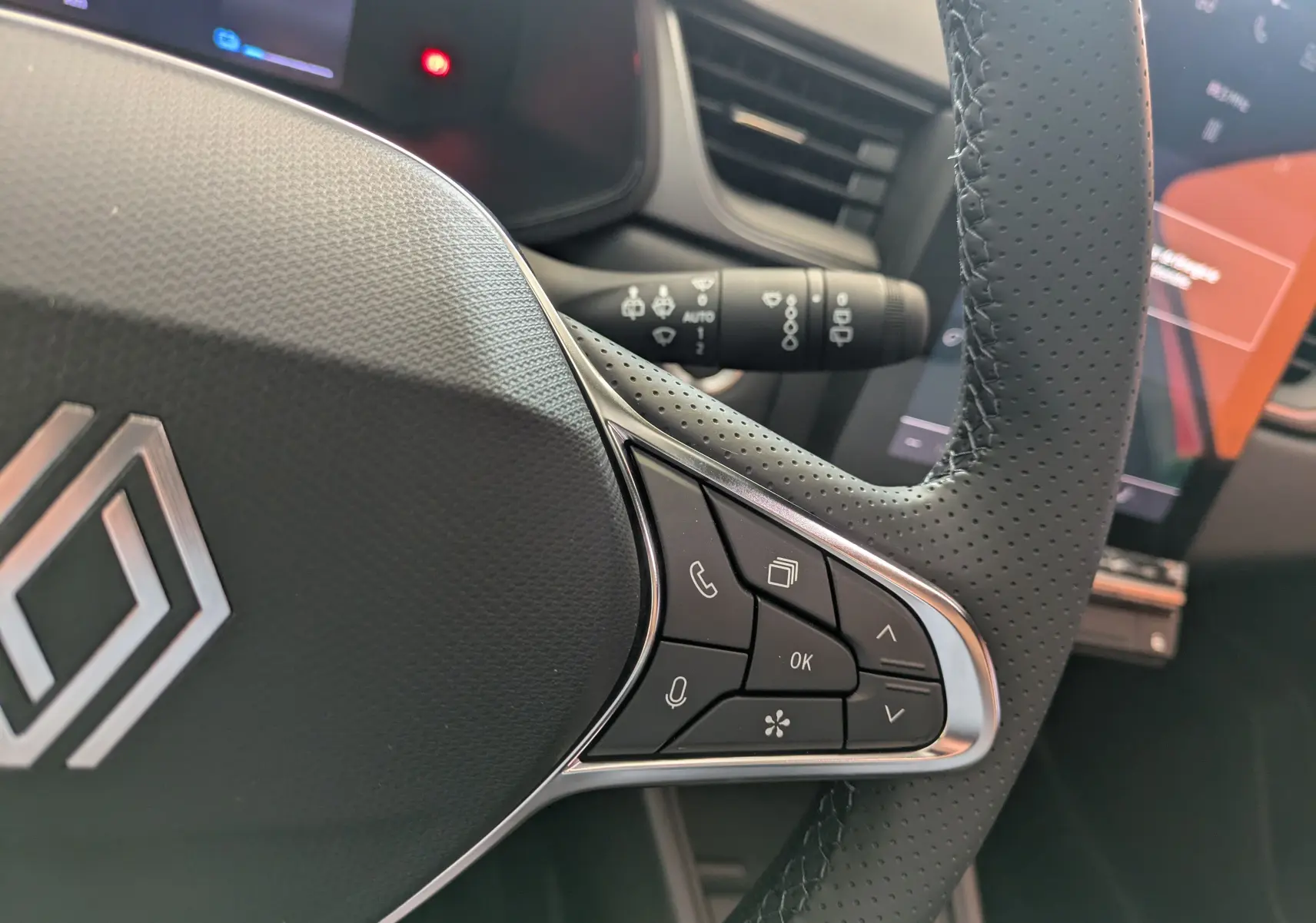 Gros plan sur les commandes à droite du volant perforé du Renault Captur E-Tech hybride 2025, intérieur noir.