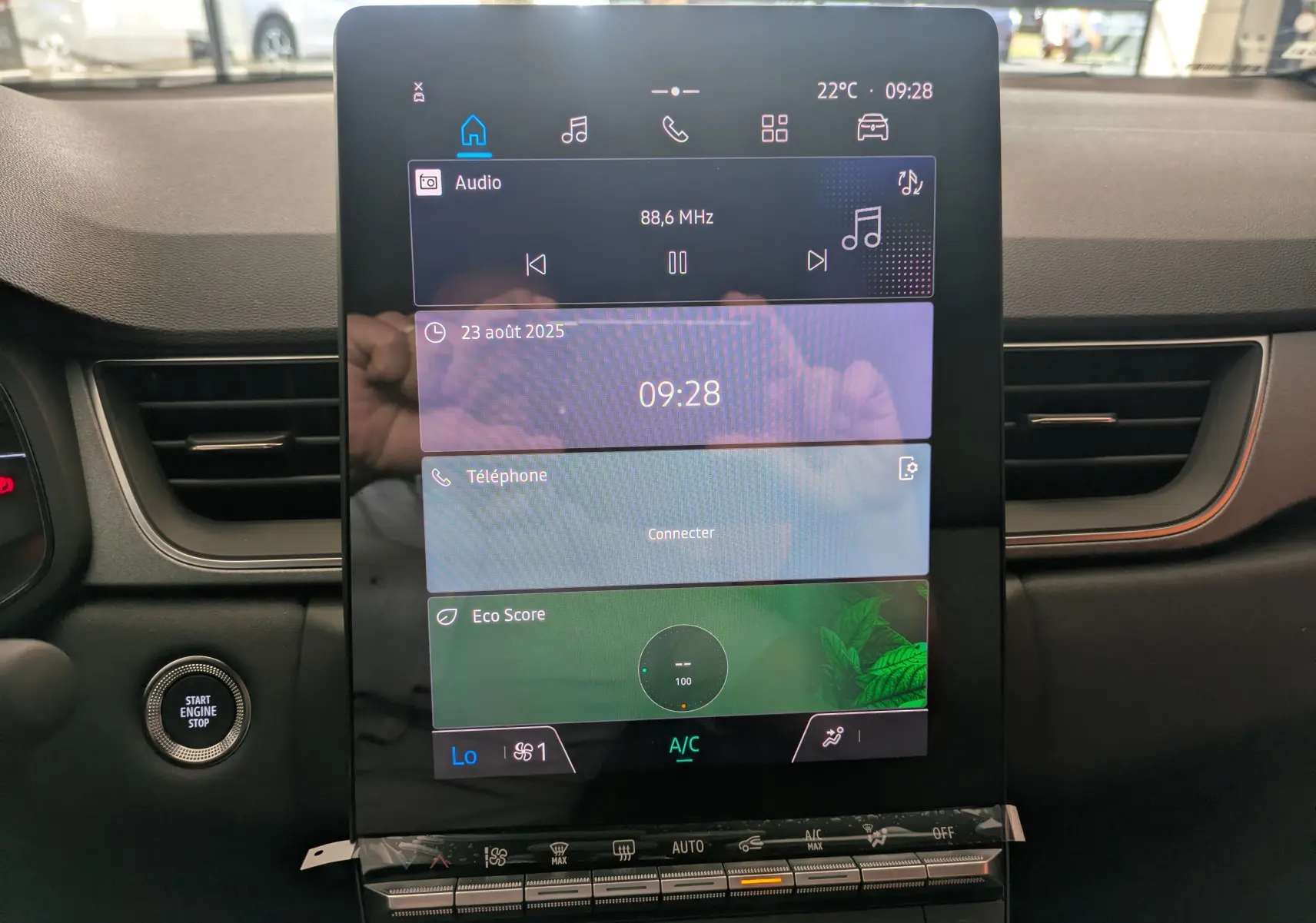 Écran tactile central vertical du tableau de bord du Renault Captur E-Tech 2025 avec commandes climatisation et bouton start/stop visible.