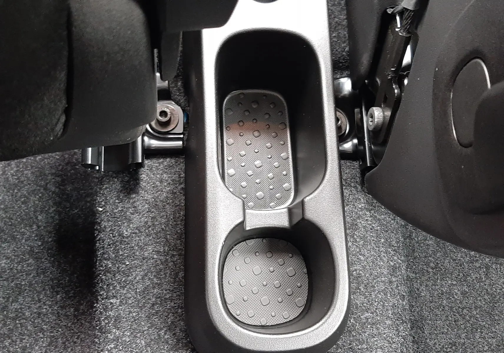 Gros plan sur le rangement central noir entre les sièges avant de la Fiat Panda 2025 blanc gelato, intérieur tissu noir.