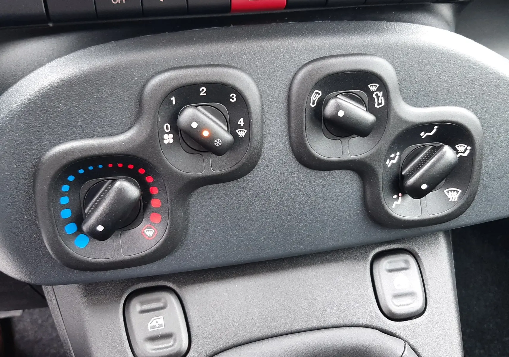 Commandes de climatisation et boutons de tableau de bord noir dans l'habitacle de la Fiat Panda 2025.