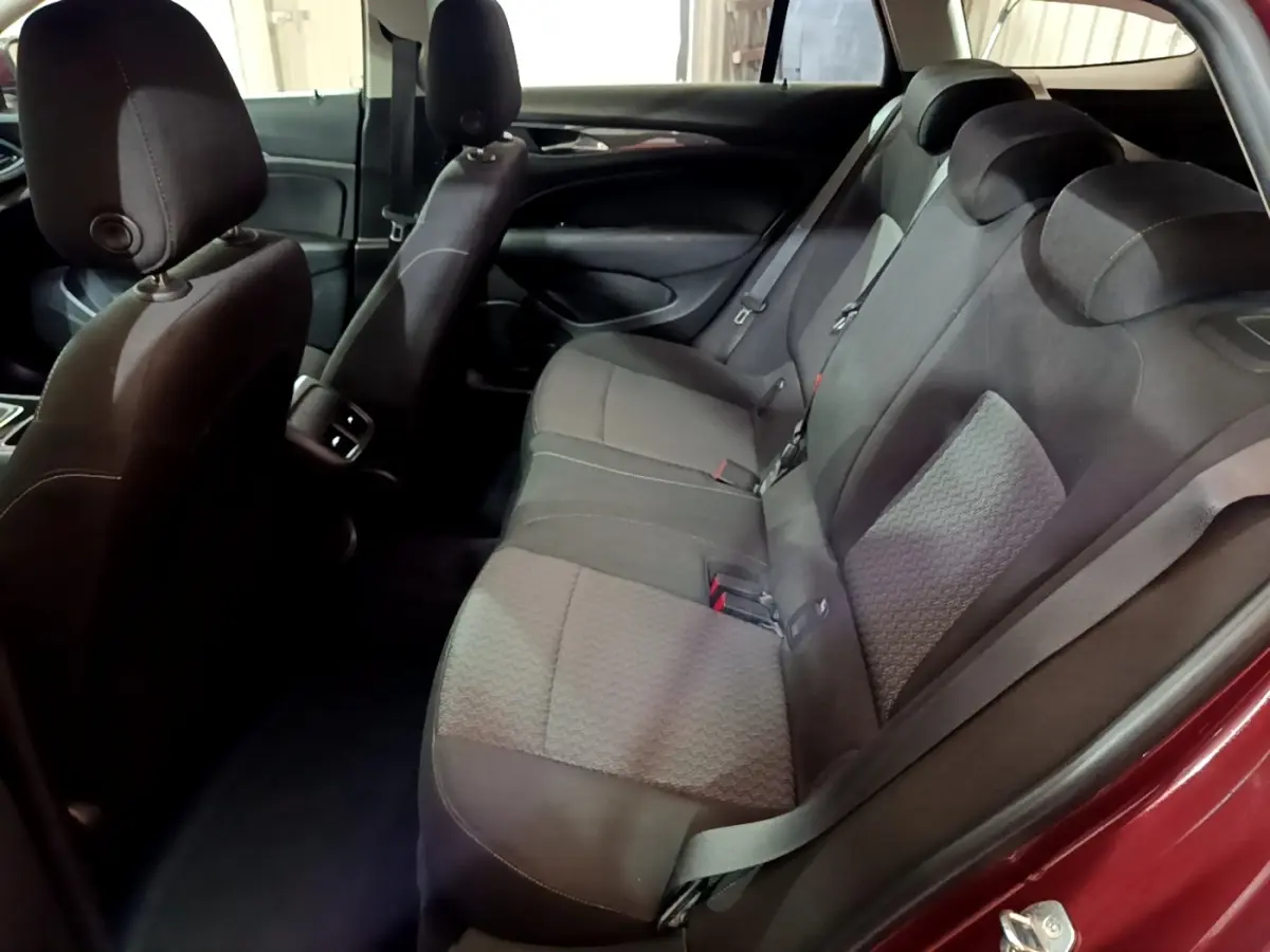 Vue intérieure côté droit sur la banquette arrière grise de l’Opel Insignia rouge, avec appuie-têtes et ceintures visibles.