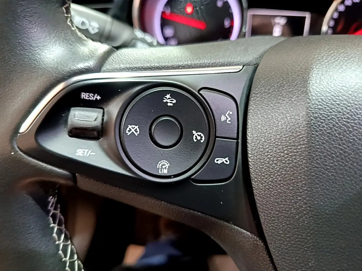 Gros plan sur les commandes de régulateur de vitesse au volant cuir noir de l’Opel Insignia rouge 2019.