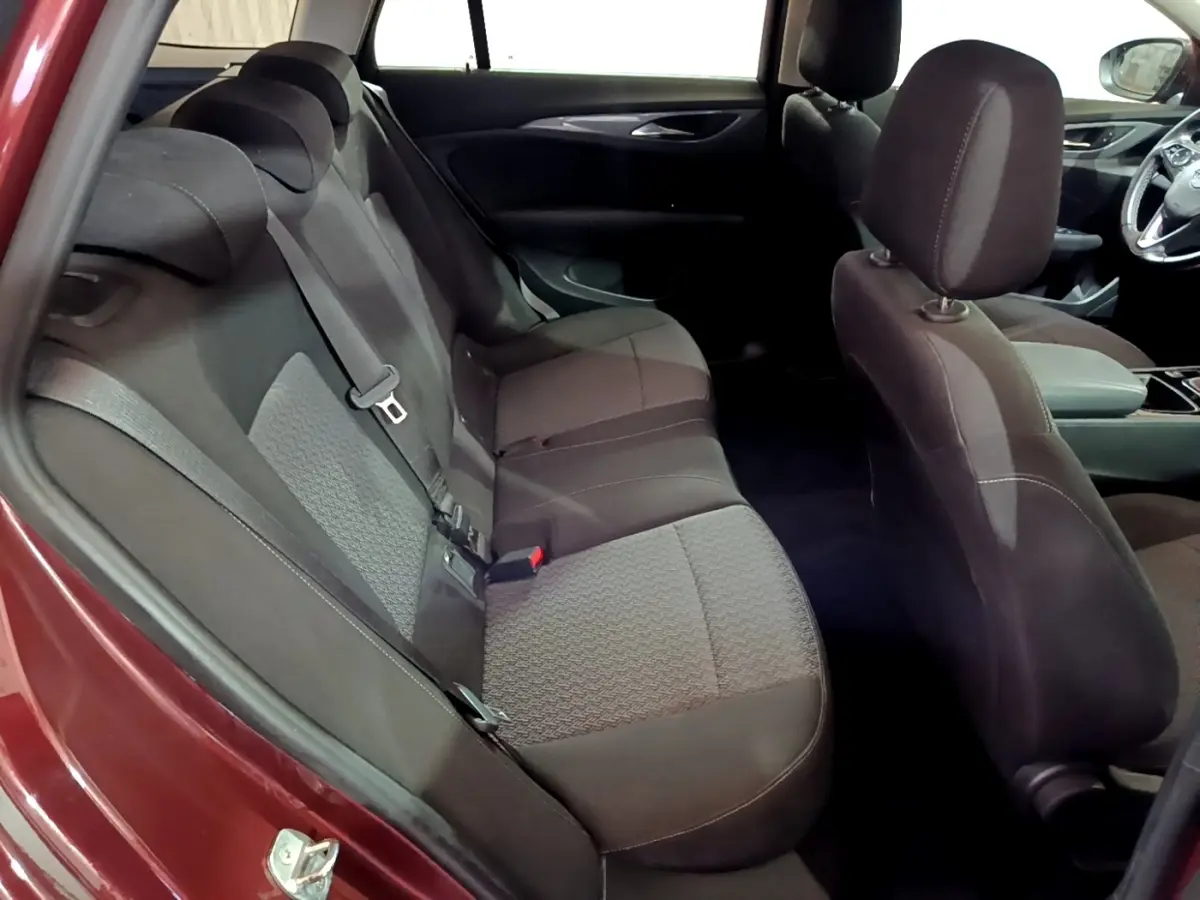 Vue intérieure côté gauche sur la banquette arrière noire de l'Opel Insignia rouge, avec sièges tissu et ceintures visibles.