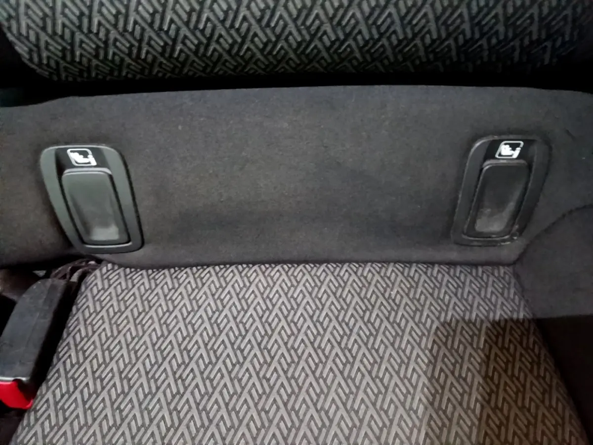 Détail des commandes de rabattement des sièges arrière sur la banquette tissu gris foncé de l'Opel Insignia.