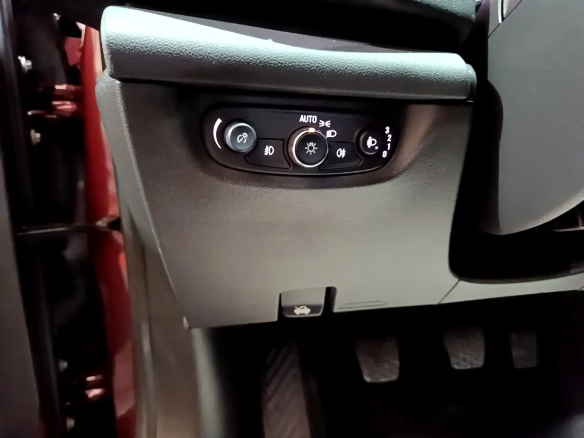 Vue rapprochée du panneau de commandes d’éclairage côté gauche dans l’habitacle d’une Opel Insignia rouge.