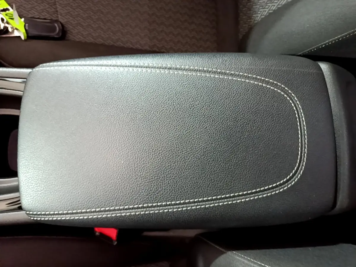 Gros plan sur l'accoudoir central en cuir noir avec surpiqûres blanches dans l'habitacle de l'Opel Insignia rouge.