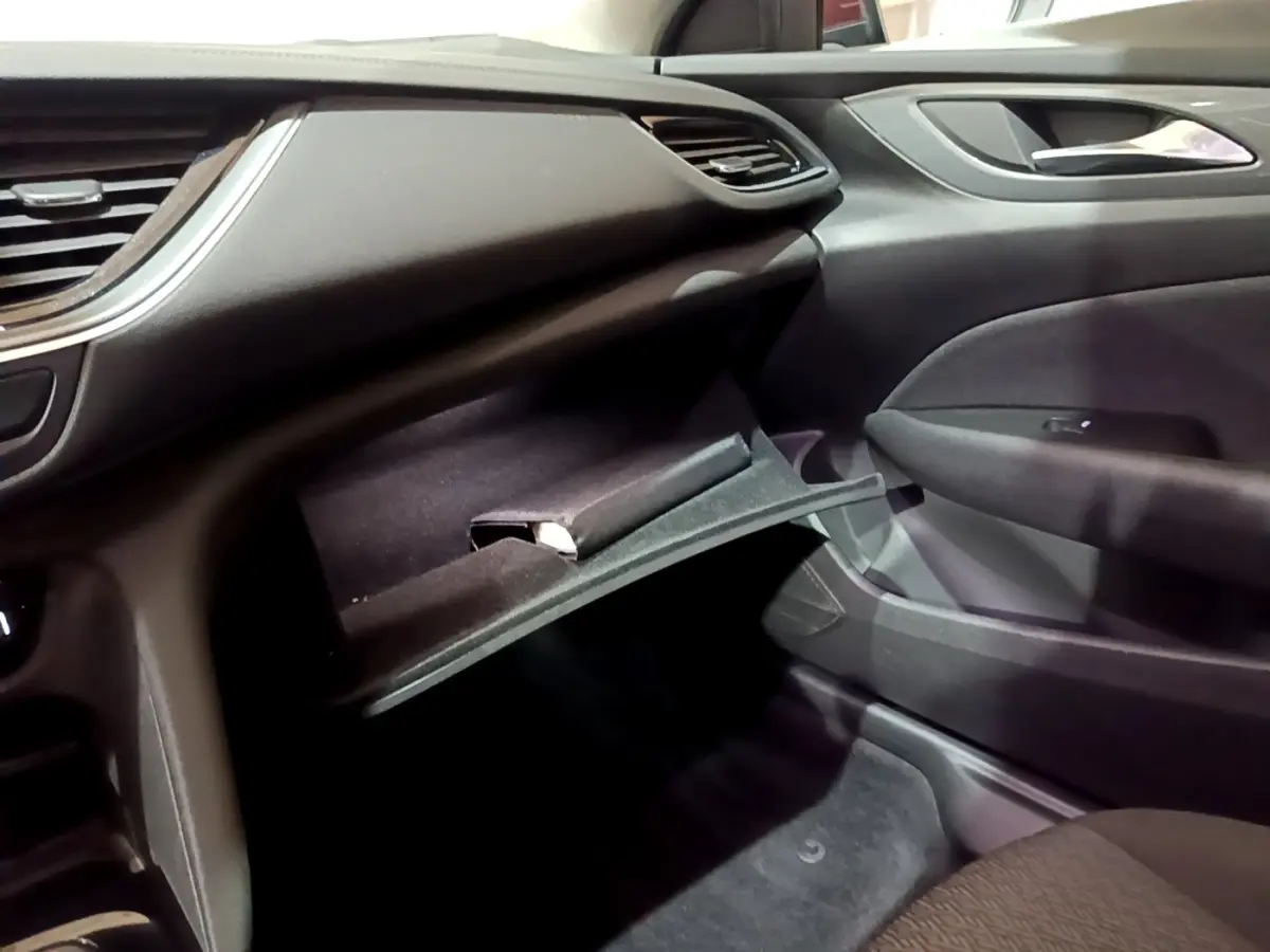Vue intérieure côté passager de l’Opel Insignia 2019 avec boîte à gants ouverte et tableau de bord noir.