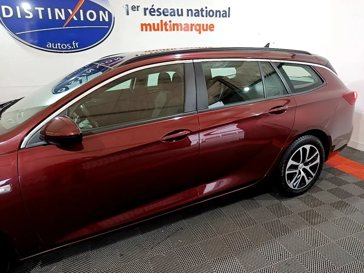 Vue de profil côté gauche d’une Opel Insignia rouge 2019 en version break, avec jantes alliage et rétroviseur assorti.