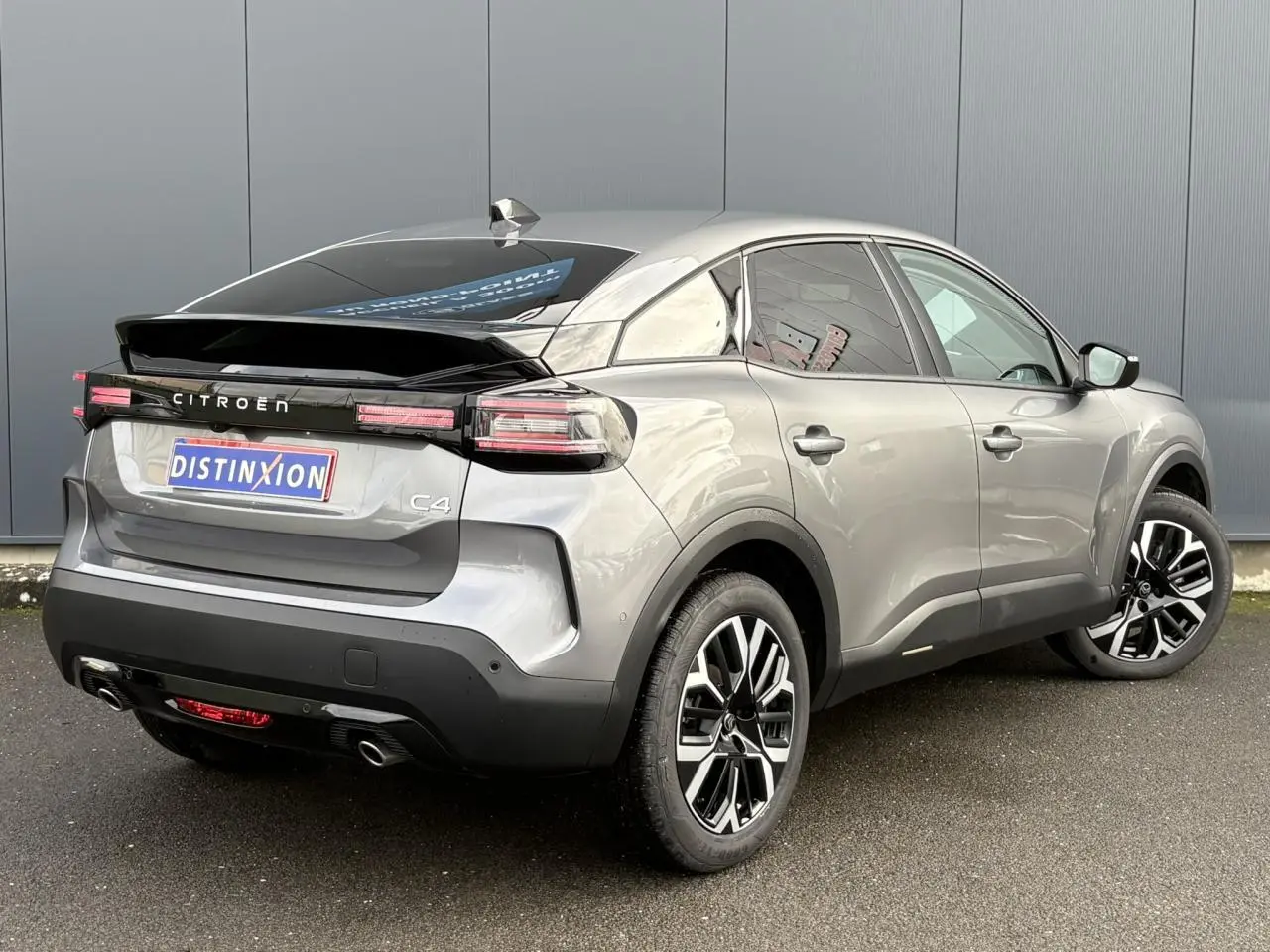 Vue 3/4 arrière droite d'une Citroën C4 Hybrid gris Mercury avec jantes alliage et toit noir brillant.
