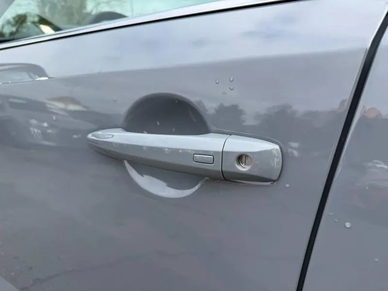 Poignée de porte côté gauche du Nissan Qashqai 2025 Hybrid e-POWER en gris argile avec bouton d'ouverture et serrure visible.
