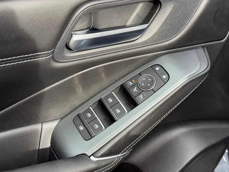 Gros plan sur la commande des vitres côté conducteur du Nissan Qashqai Hybrid e-POWER 2025, intérieur noir avec surpiqûres blanches.