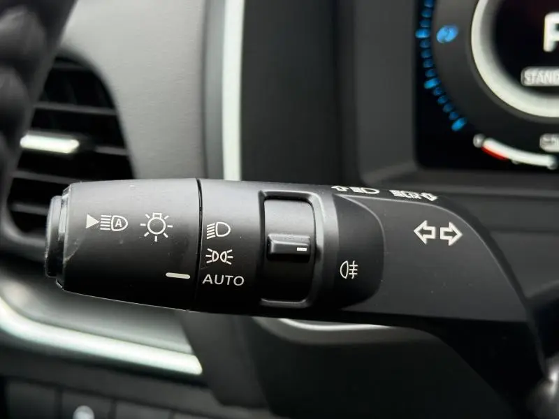 Gros plan sur la commande des phares et clignotants du Nissan Qashqai Hybrid e-POWER 2025, intérieur noir.