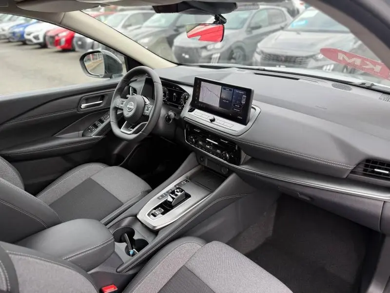 Vue intérieure côté conducteur du Nissan Qashqai Hybrid e-POWER 2025, tableau de bord moderne avec écran tactile central.