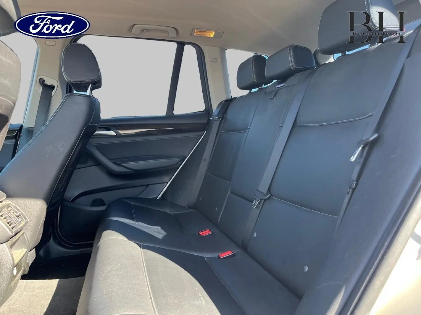 Vue latérale droite de la banquette arrière en cuir noir du BMW X3 Mineralsilber, avec appuis-tête et ceintures visibles.
