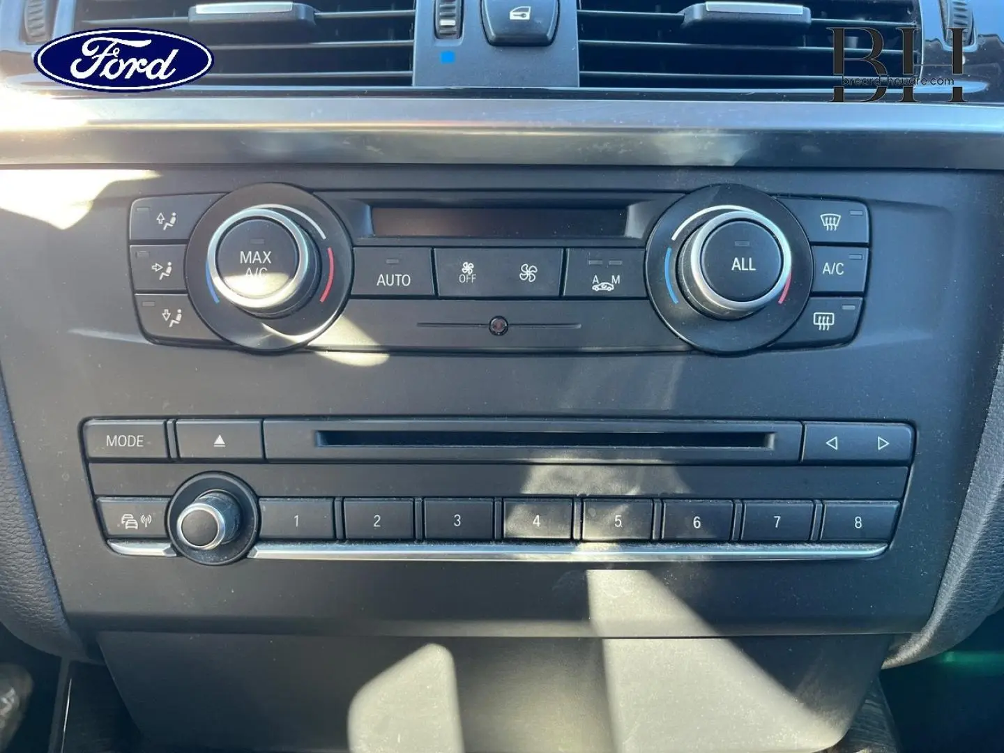 Panneau de commande central intérieur d'une BMW X3 Mineralsilber, avec réglages climatisation et radio visibles.