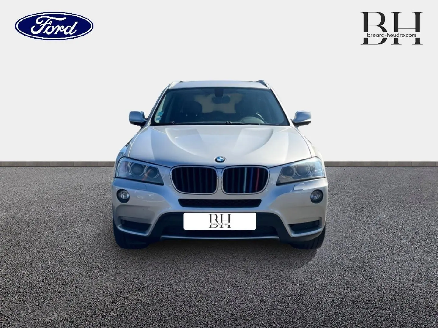 Vue avant d'un BMW X3 Mineralsilber 2013 avec calandre noire et phares halogènes allumés.