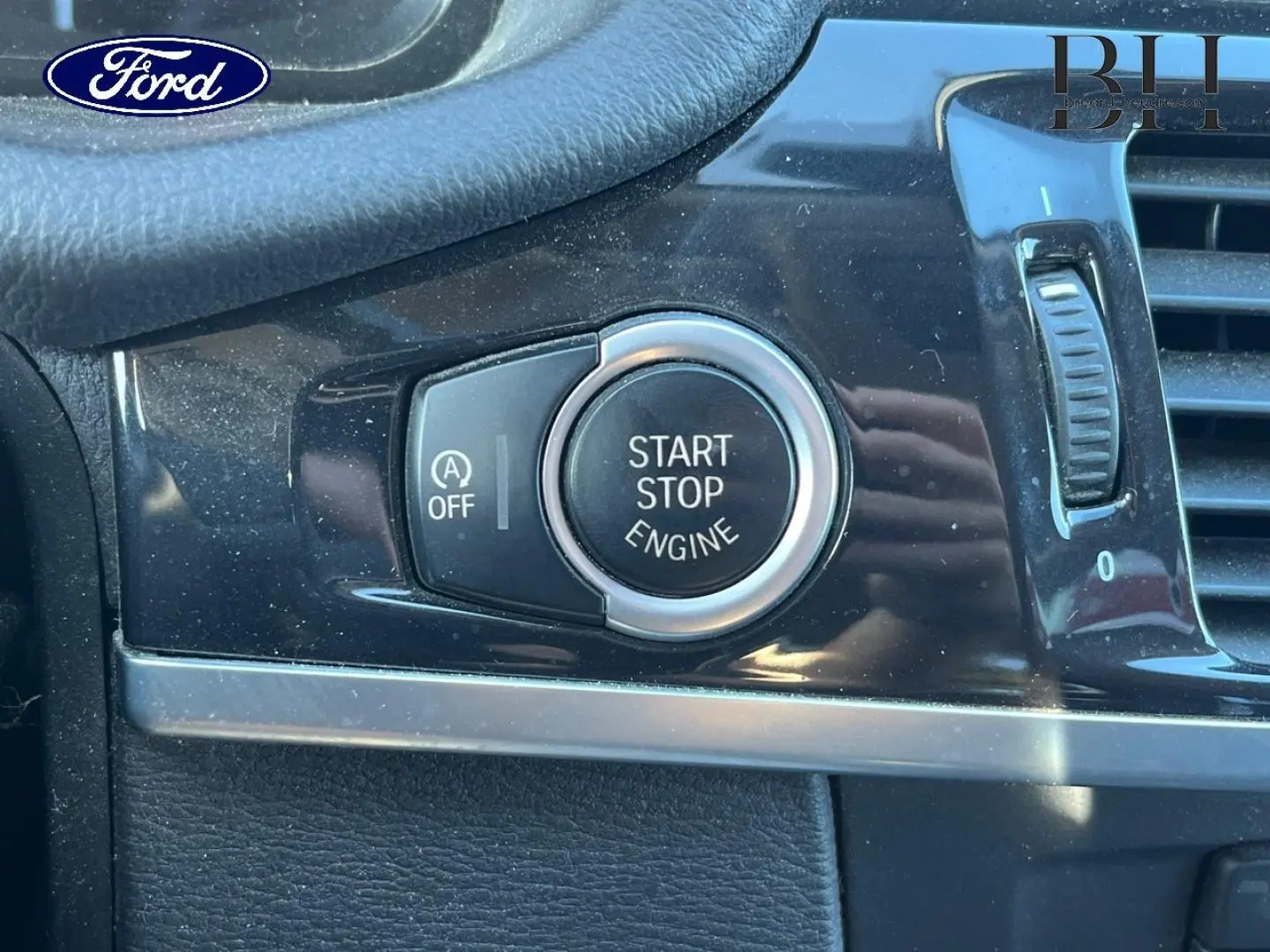 Bouton démarrage/arrêt moteur en gros plan sur tableau de bord noir brillant d'un BMW X3 Mineralsilber, vue intérieure rapprochée.