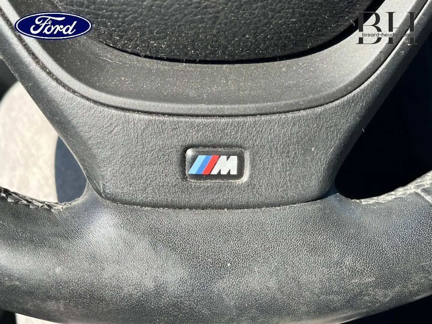 Gros plan sur le volant cuir avec logo M d'une BMW X3 Mineralsilber, mettant en valeur la finition sportive.