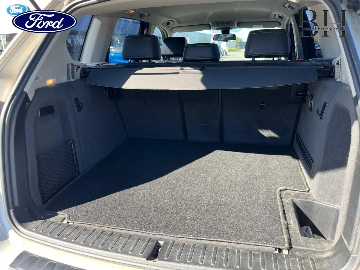 Coffre ouvert vu de l'arrière d'un BMW X3 Mineralsilber 2013, avec cache-bagages et banquette arrière visible.