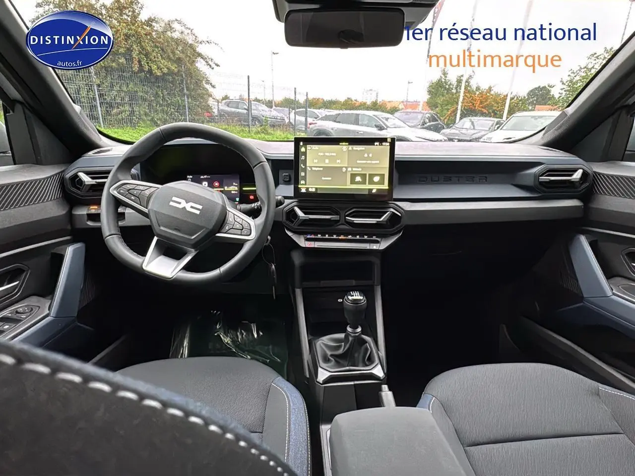 Vue intérieure avant du Dacia Duster 2025 avec tableau de bord moderne, écran tactile et volant multifonction noir.