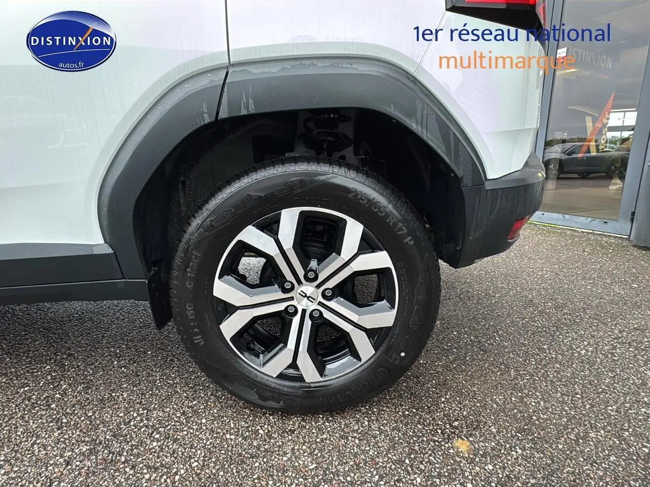 Gros plan sur la roue arrière droite du Dacia Duster blanc Arctic avec jante alliage et passage de roue noir.