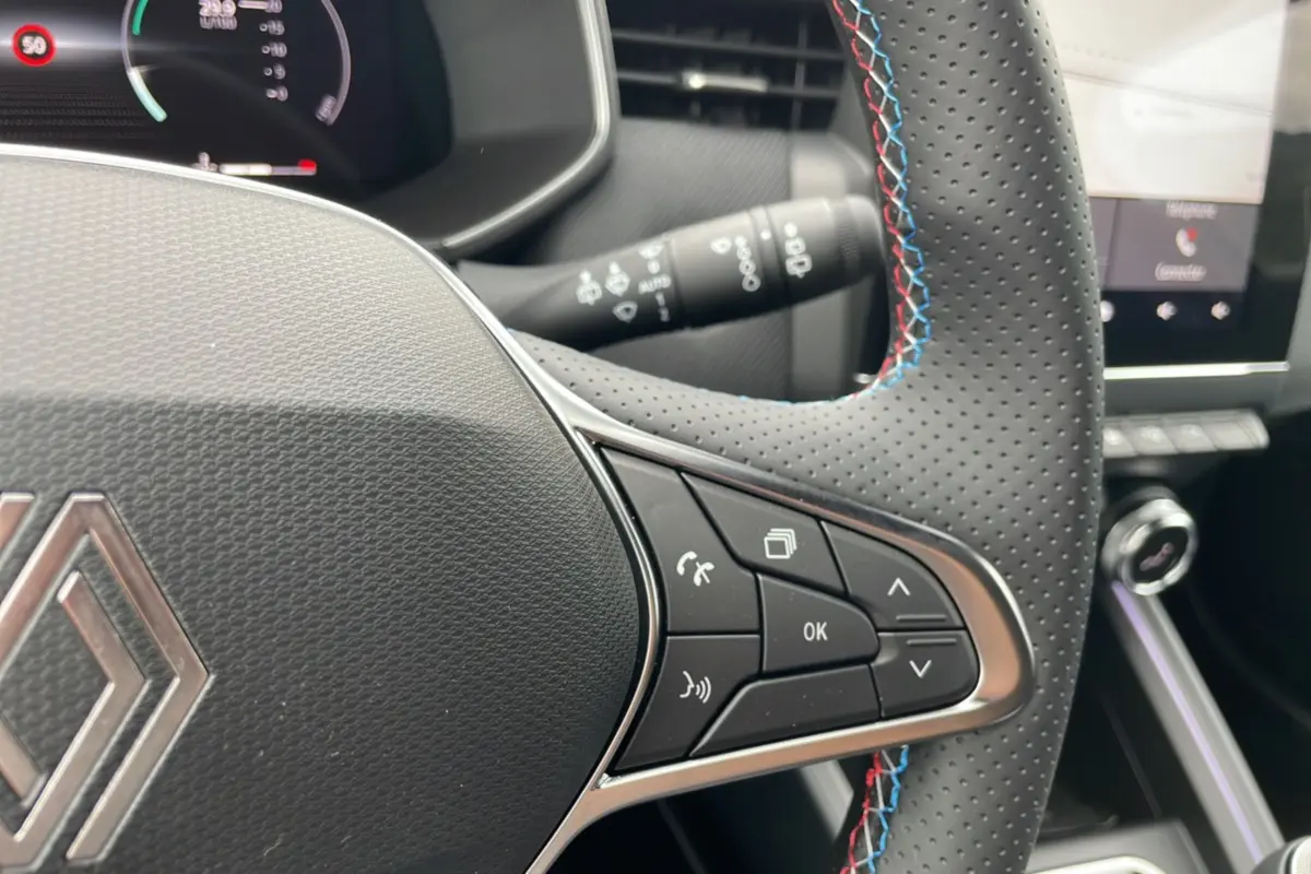 Gros plan sur le volant perforé avec surpiqûres tricolores de la Renault Clio V E-Tech 145 Esprit Alpine 2025.
