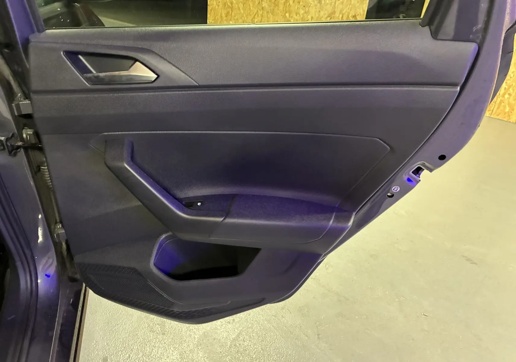 Porte arrière gauche ouverte d'une Volkswagen Polo gris 2025, montrant la garniture intérieure noire et la poignée intégrée.