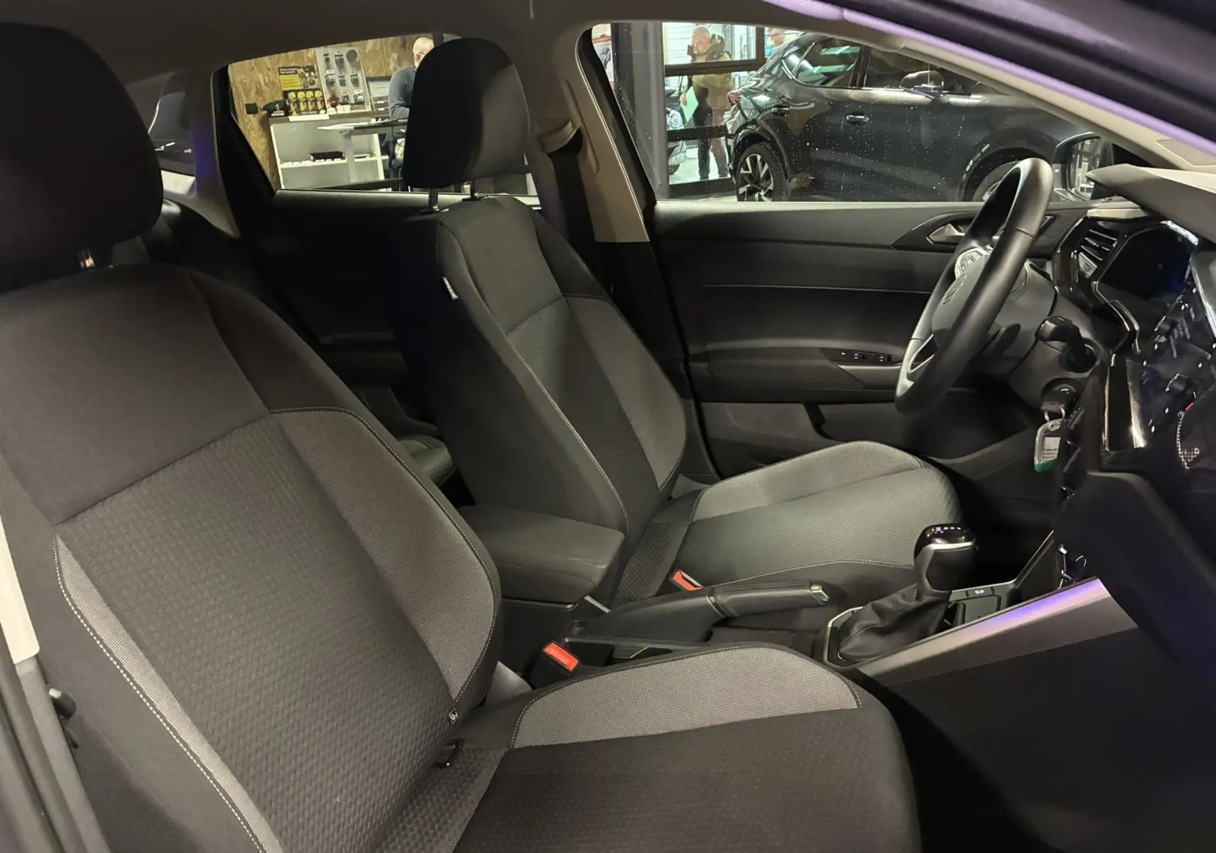 Vue intérieure côté conducteur de la Volkswagen Polo gris 2025, sièges tissu noir et console centrale avec boîte auto.