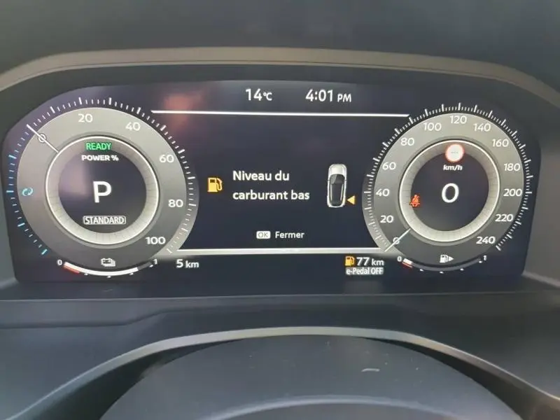 Tableau de bord numérique du Nissan Qashqai Hybrid e-POWER 2025 affichant un avertissement de carburant bas.