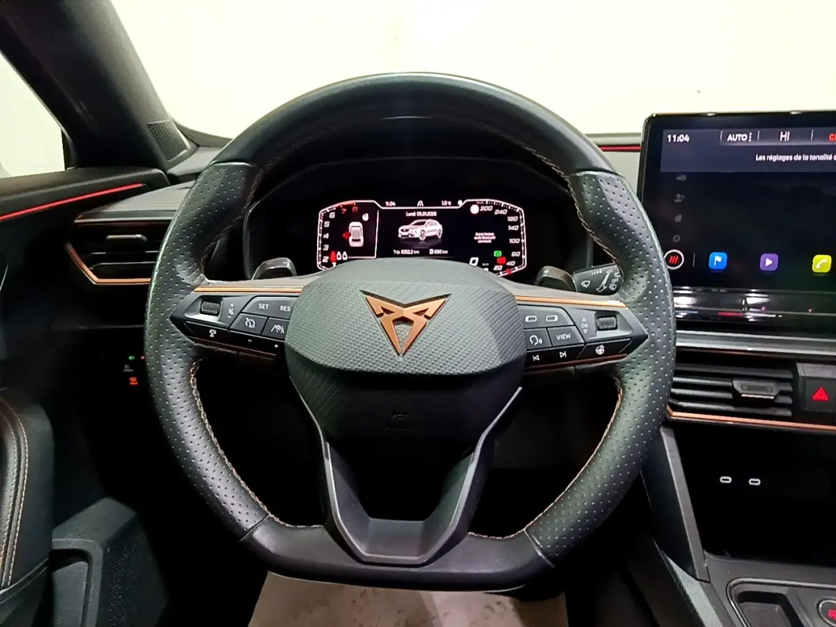 Vue intérieure centrée sur le volant cuir et alu perforé de la CUPRA Formentor 2024 avec tableau de bord digital et écran tactile.